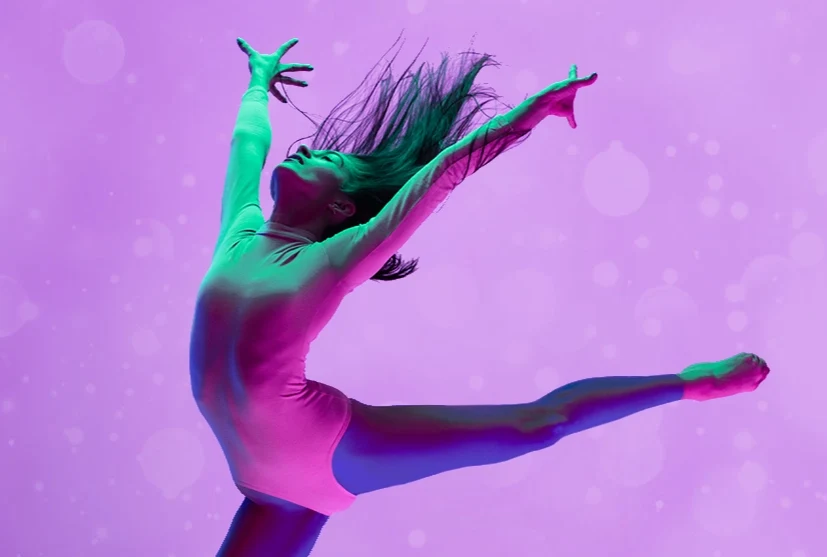 Dancer performs with hands outstretched and hair flying against a pink background
