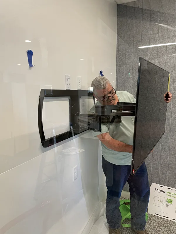 Technician mounting a monitor to the wall