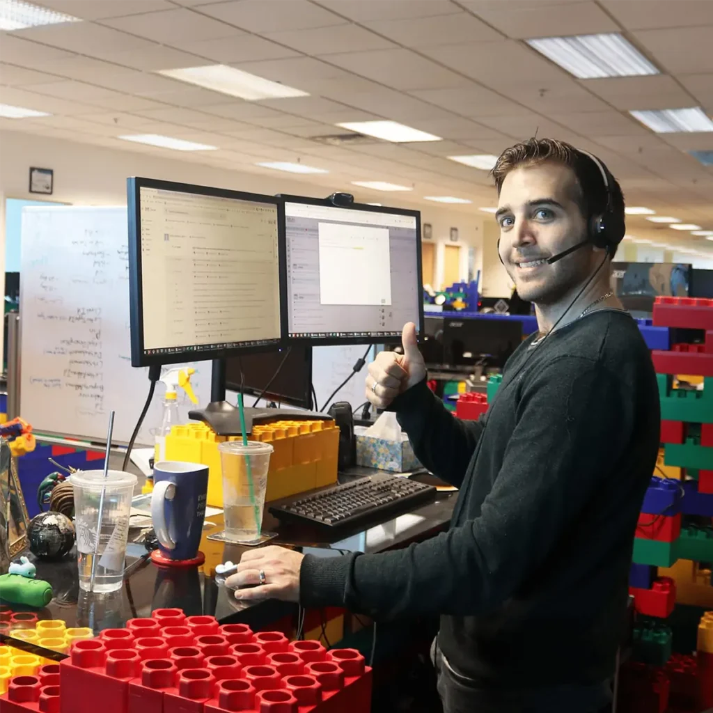 Web developer and website designer from the marketing services team discuss a web design project in front of computers in the Miles headquarters building