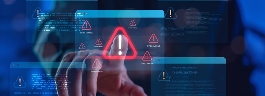 Alert icons and cybersecurity warnings overlay a person working on a computer, with prominent red warning triangles and messages about malware, ransomware, and digital security.