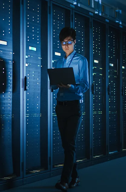 Male IT specialist walks along the row of operational server racks