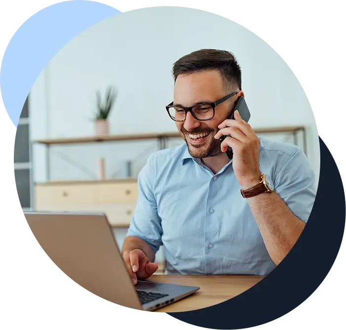 Businessman talking with someone over the phone, while using laptop.