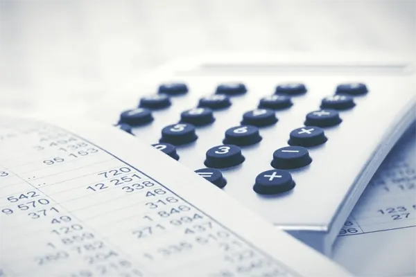 Calculator lying on a desk next to a sheet of paper detailing a business's budget