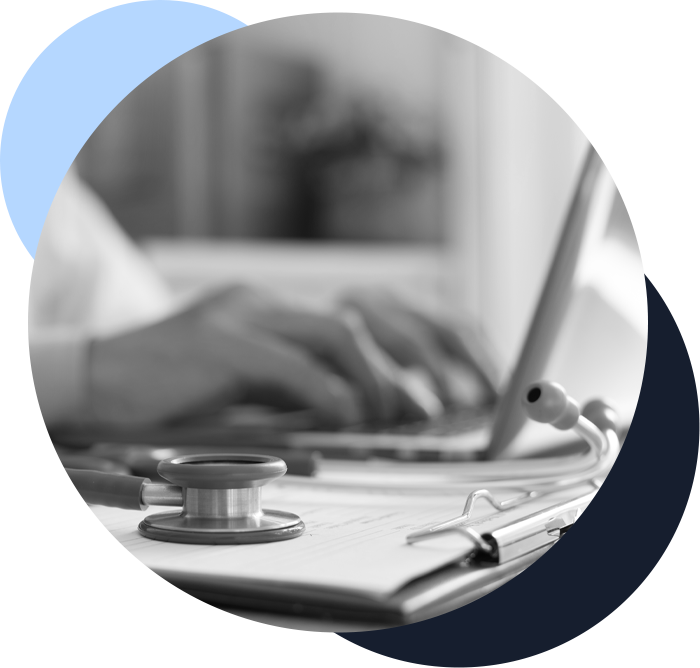 Doctor working on laptop computer and medical stethoscope on clipboard on desk
