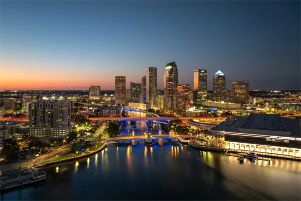 Tampa, Florida. Downtown district of American city after sunset with brightly illuminated high buildings and highway bridge traffic.