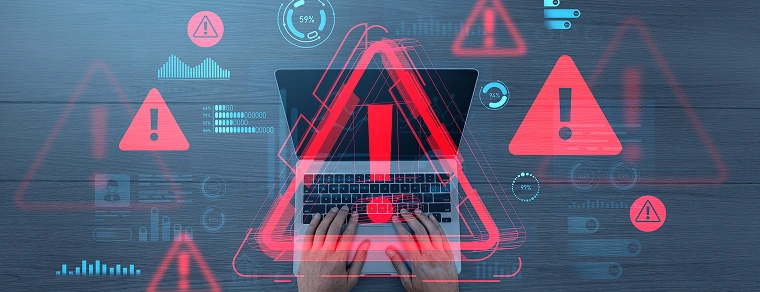 Hands typing on laptop surrounded by red digital warning symbols and data graphics, on a creative blue-toned background, concept of cybersecurity threats