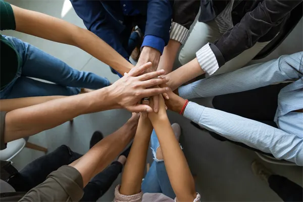 Close up top view of diverse businesspeople stack hands motivated for shared business success at briefing, multiracial colleagues engaged in teambuilding activity show unity support at office meeting