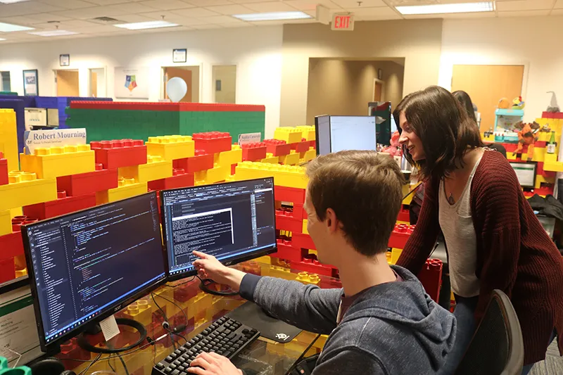 Software team points at computer to troubleshoot software challenges