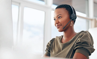 A woman with a headset looks at a computer offscreen and types