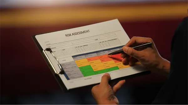 Detailed closeup hand holds clipboard analyzing operational risk assessment matrix chart to ensure safety and security focused workplace